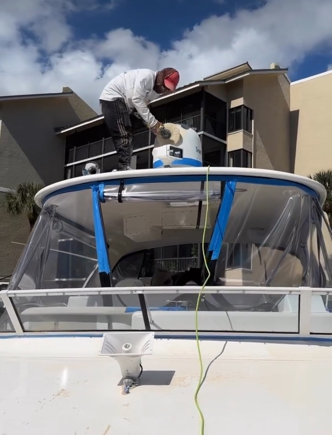 A man applies paint to the front of a boat, focusing on detail and craftsmanship in a sunny outdoor setting.