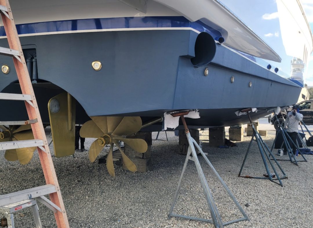 A man repairs a boat, focused on maintenance tasks in a workshop setting.